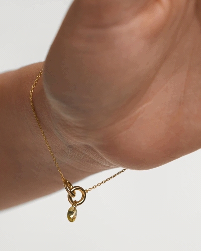 Pulsera con dos anillos entrelazados y un colgante de circonita verde en forma de gota