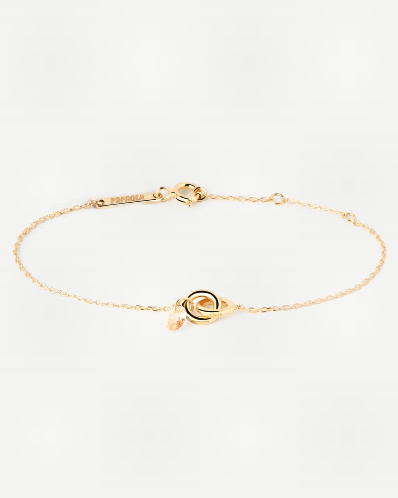 Pulsera con dos anillos entrelazados y un colgante de circonita melocotón en forma de gota.