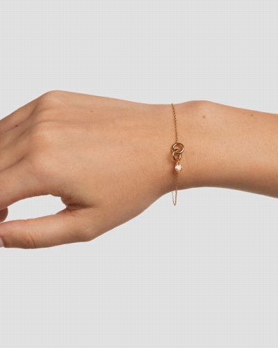 Pulsera con dos anillos entrelazados y un colgante de circonita melocotón en forma de gota.