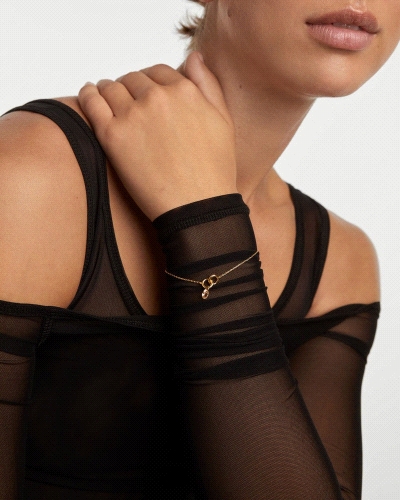 Pulsera con dos anillos entrelazados y un colgante de circonita melocotón en forma de gota.