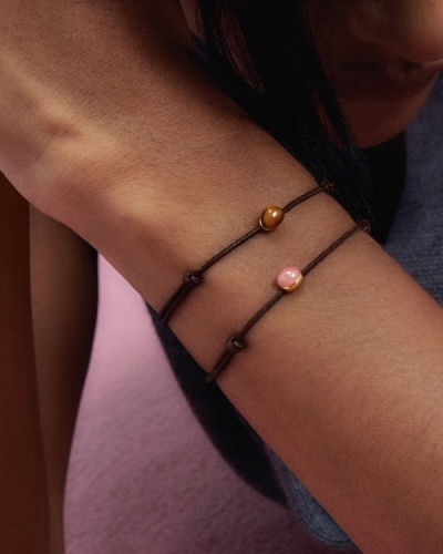 Pulsera de cordón negro ajustable con diseño de piedra rosada.
